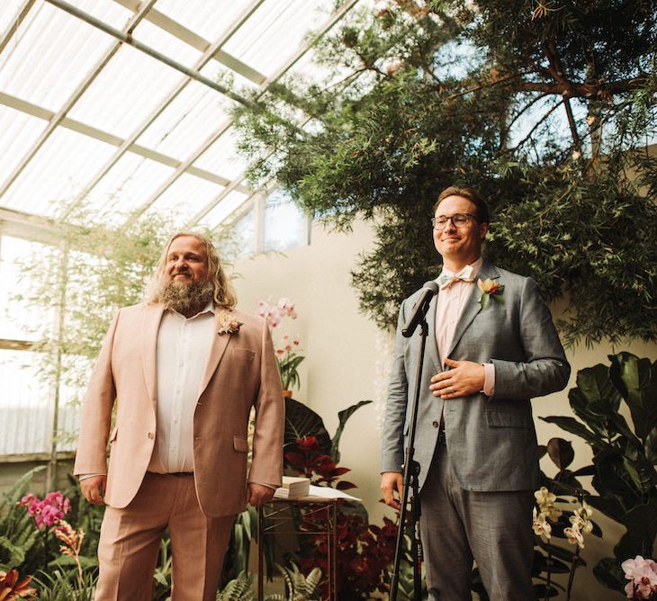 Celebrant and groom in a pink suit standing at the altar 