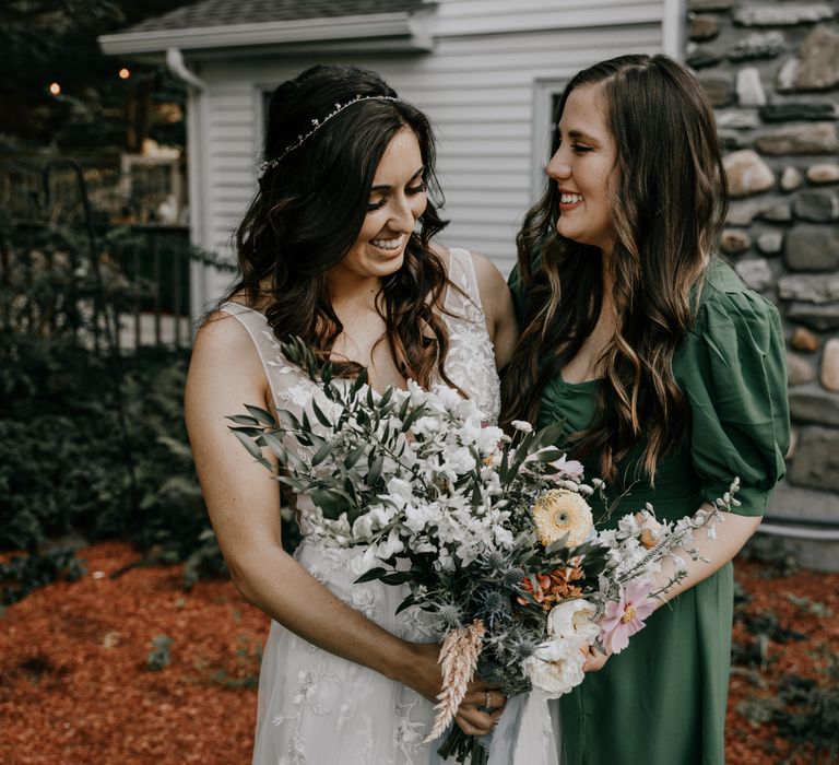 Bride laughs with wedding guest whilst holding bouquet