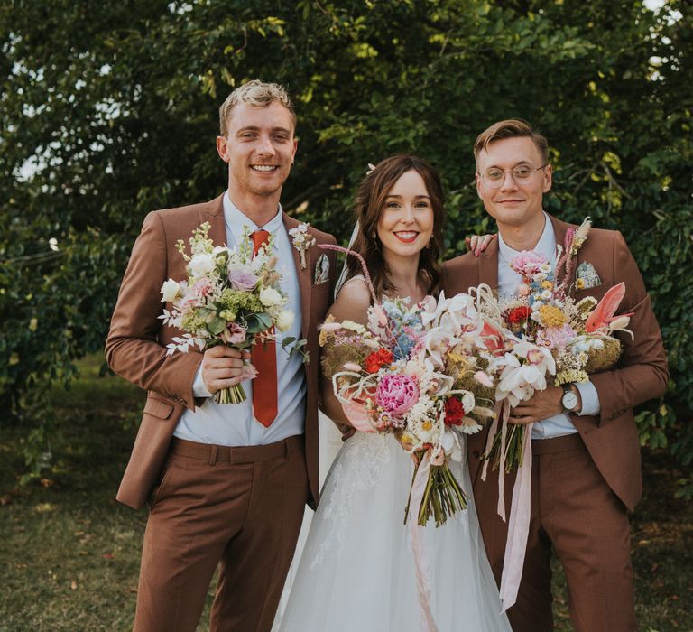 Bride stands with her friends on the day of her wedding holding floral bouquets