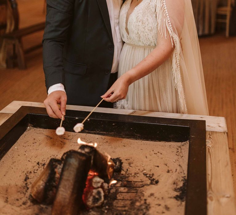 Bride & groom toast marshmallows in wedding tipi 