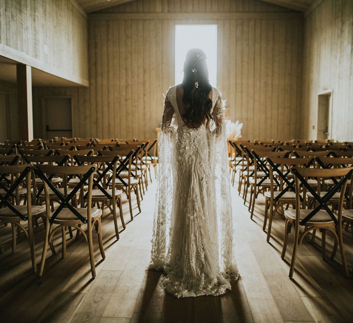 Bride in a lace wedding dress with long bell sleeves standing in the ceremony room at Primrose Hill Farm 