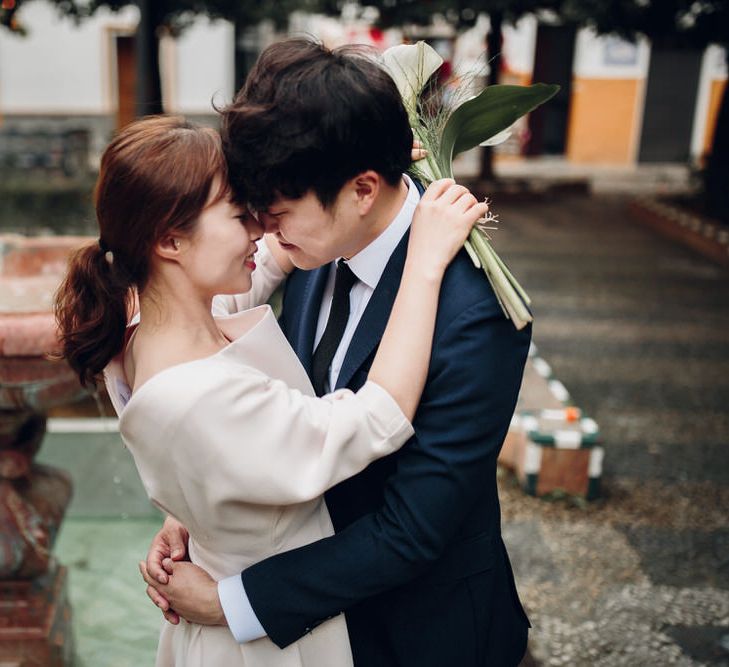 Asian couple lean in to kiss in front of fountain