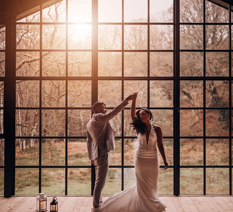 Bride & groom dance in front of large arched window as the sunlight streams through