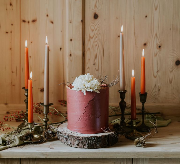 Single tier burgundy buttercream wedding cake with orange taper candle decor 