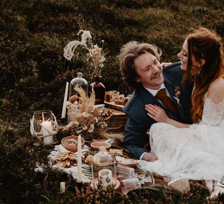 Bride & groom sit down to eco-friendly picnic on the hillside of Isle Of Skye