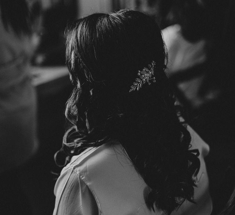 A black and white close up image of a bride's half up half down hair style with large jewelled hair slide.