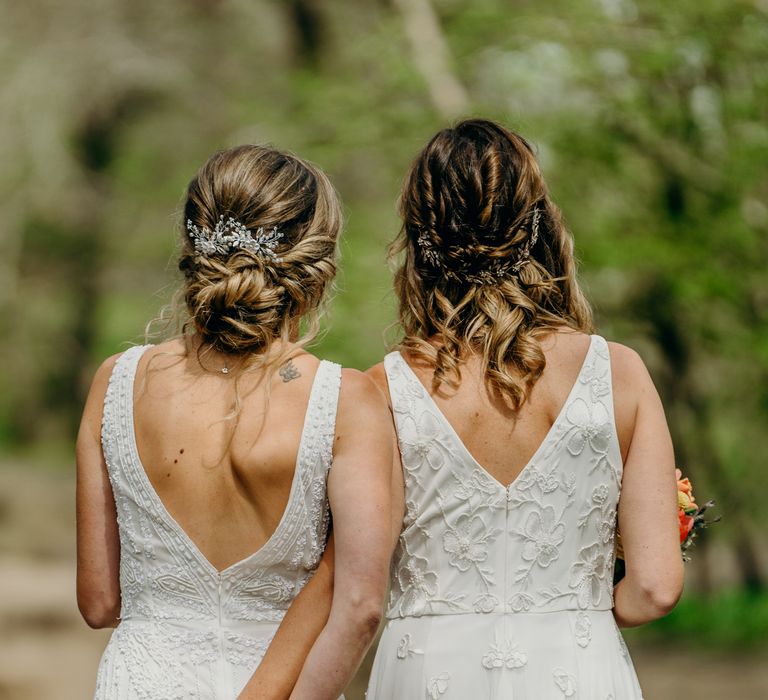 Brides stand with their backs to the camera whilst holding hands