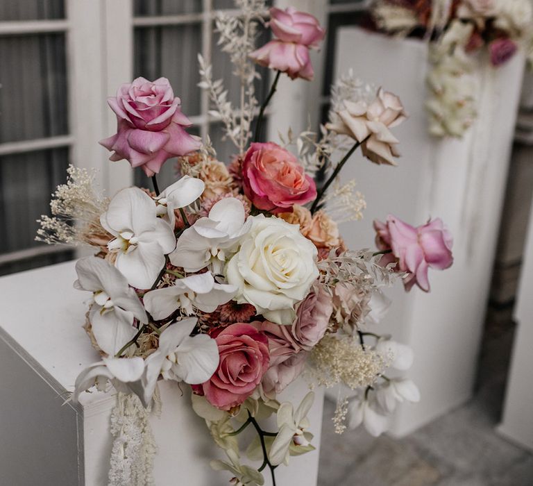 Romantic wedding flower arrangement with white orchids and pink peeled back roses 