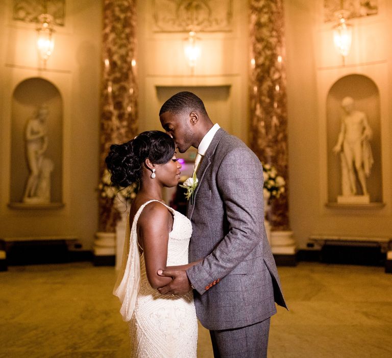 Bride & groom embrace one another as the lights shine around them in stately room