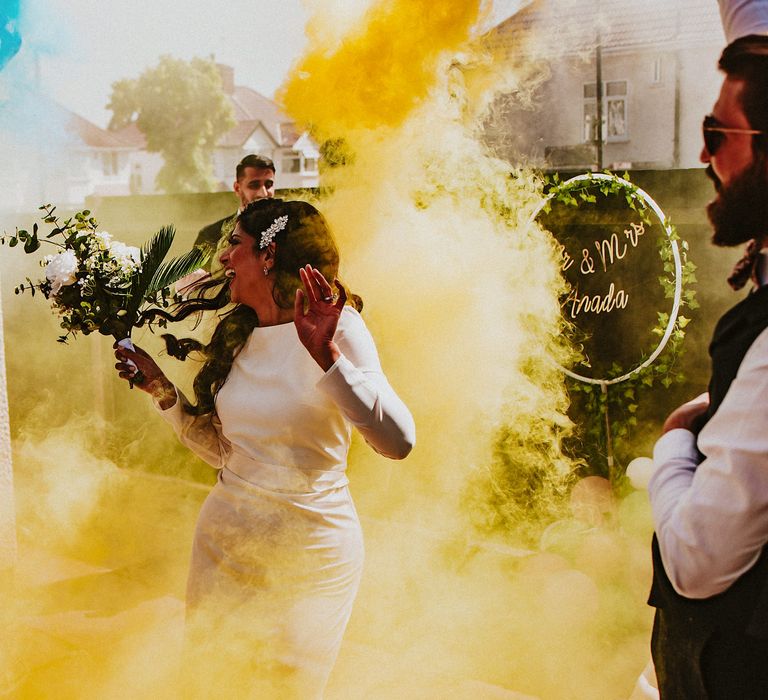 Bride and groom entering their garden party wedding reception with colourful smoke bombs 