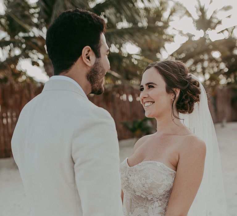 Bride & groom look lovingly at one another on the beach 