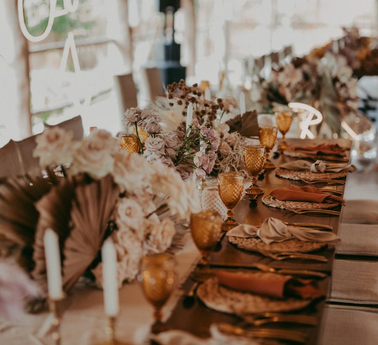 Boho chic tablescape complete with burnt orange napkins and pastel florals