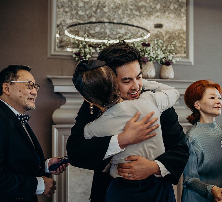 Bride and groom embracing their wedding guests at their registry office wedding 