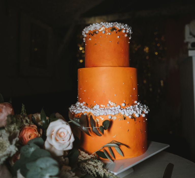 Orange three-tier wedding cake with white ball wedding decor 