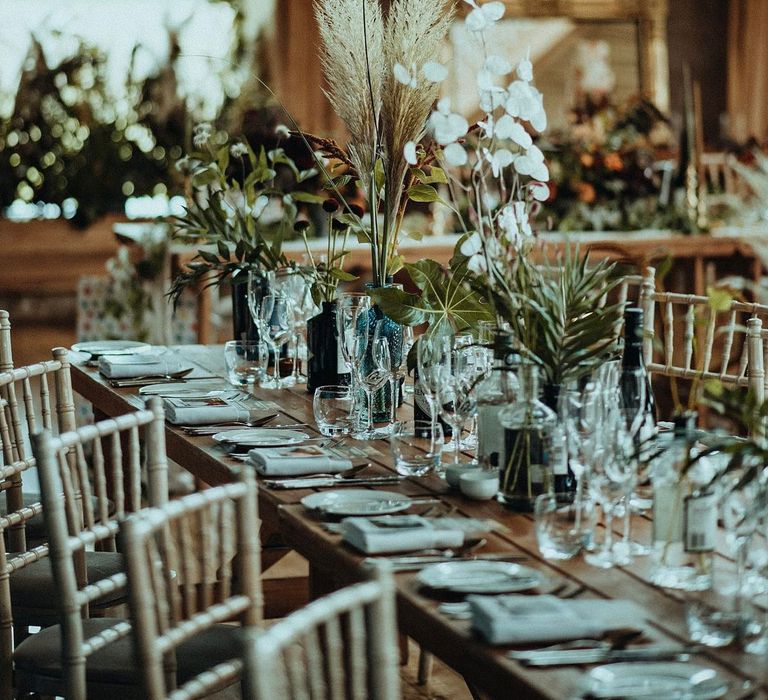 Rustic tablescape set on wooden table complete with green foliage