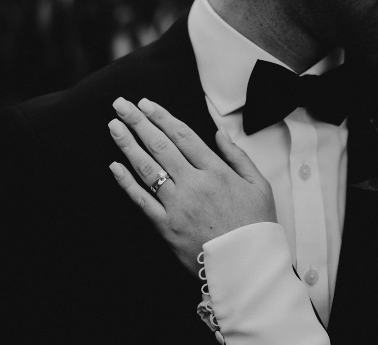 Bride with square cut manicure rest her hand on her grooms chest in a long sleeve wedding dress with buttons on the cuff 