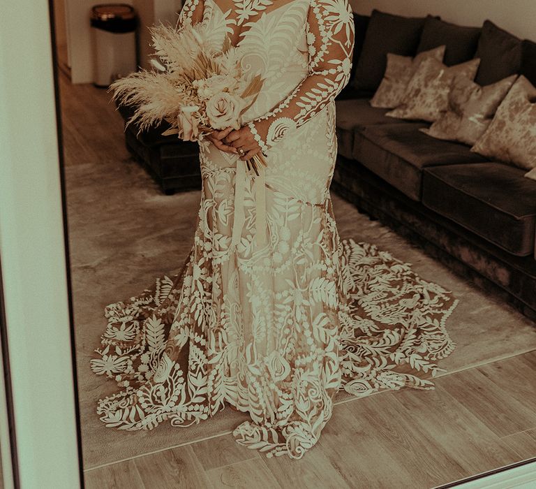 Indian bride in the Avril Rue de Seine wedding dress with lace detail, long sleeves and puddle train holding a dried flower bouquet 