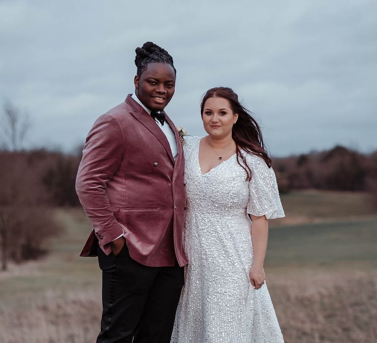 Bride & groom stand on fields on their wedding day