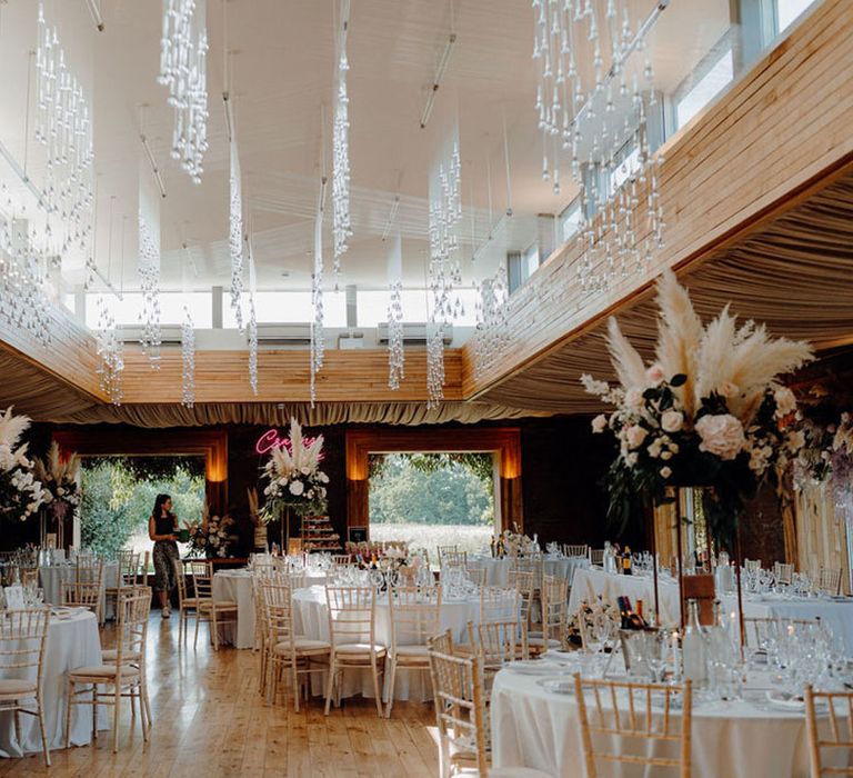 Gillyflower wedding reception at Elmore Court with tall pampas grass and rose flower centrepiece decoration and pink crazy in love neon sign 