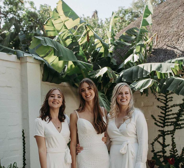 Bride in lace v-neck mermaid wedding dress with bridesmaids in white satin wrap dresses