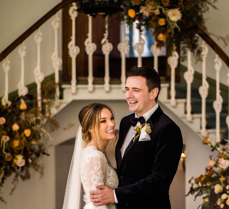 Bride and groom laughing together for black tie autumn wedding at country house