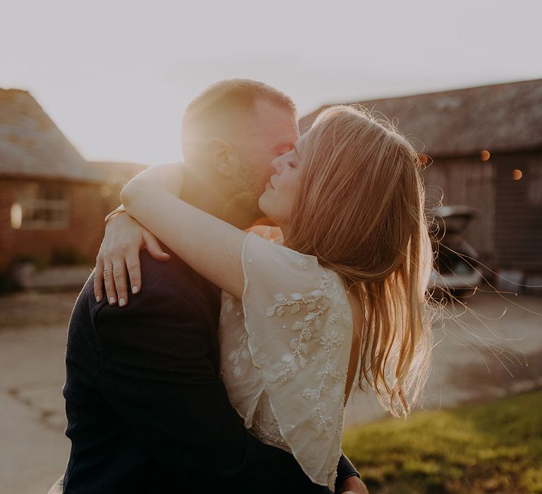 Golden hour shot of the bride giving the groom a big hug