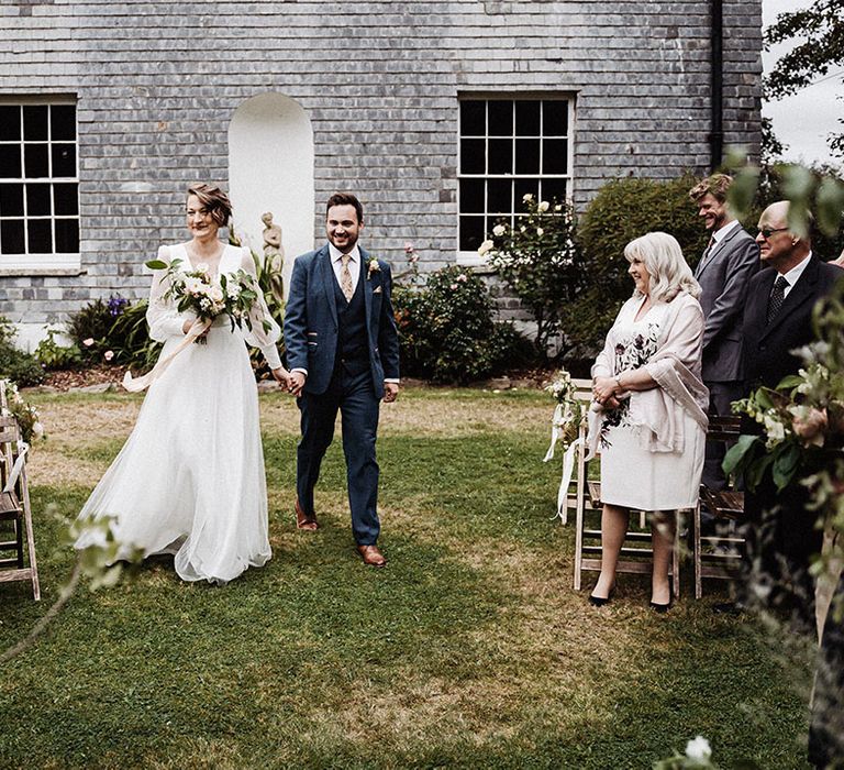 Bride and groom walk back down the aisle as a married couple