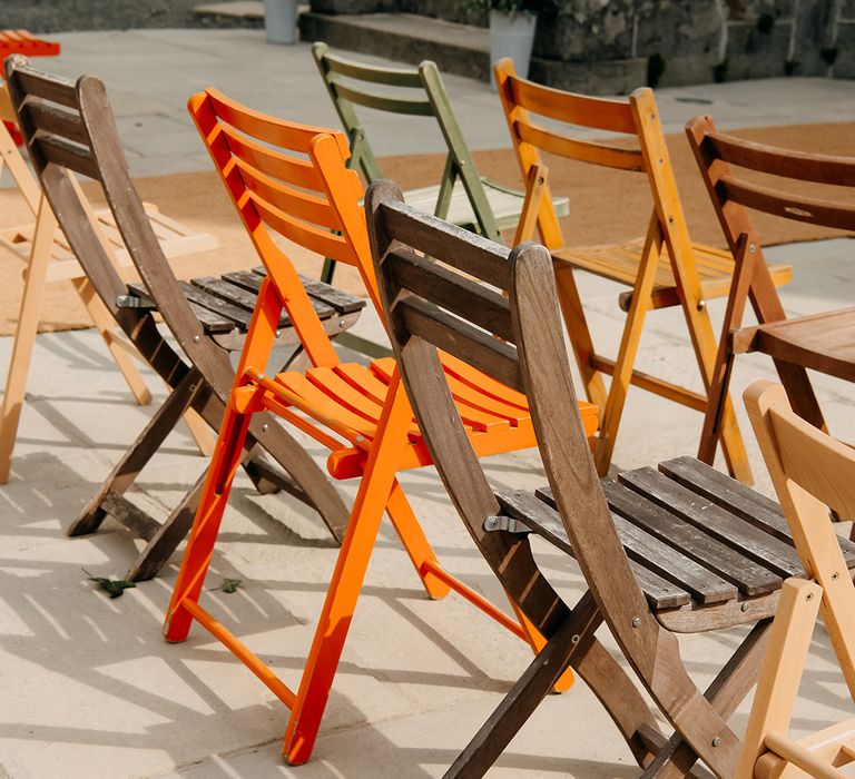 Colourful orange, yellow, green and brown fold chairs for wedding guests 