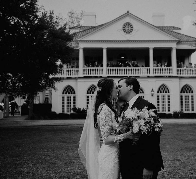 Bride and groom kiss in front of their wedding venue 