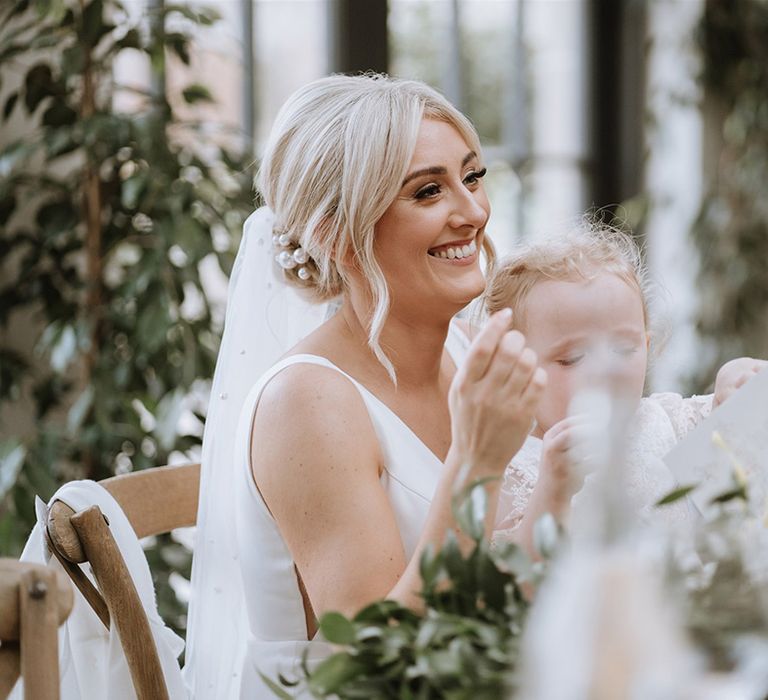 Bride smiles with pearl hair pins during wedding speeches 