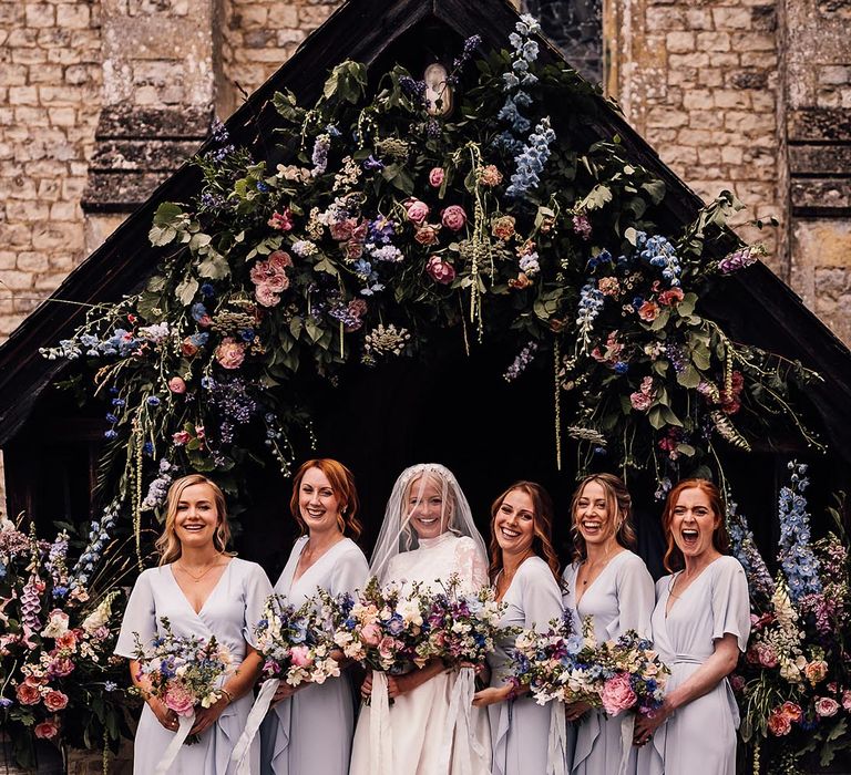 Bride in lace Jesus Peiro wedding dress with bridesmaids in pale blue dresses and matching pink and blue wedding bouquets 