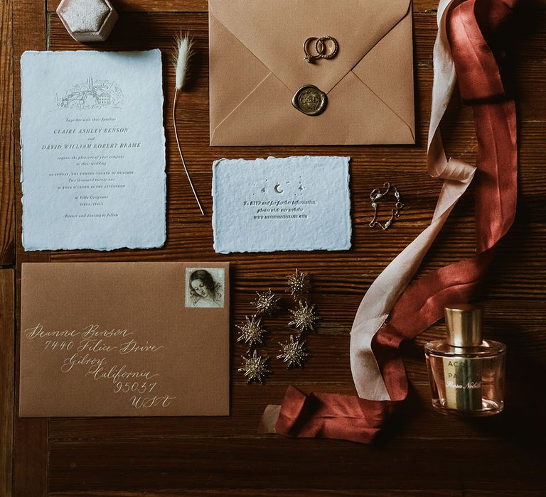 Wedding stationery with vintage Italian feel lays beside burnt orange and terracotta coloured ribbon and strappy pearl bridal shoes  