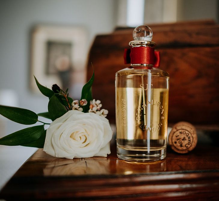 Grooms aftershave beside white roses buttonhole on wooden table the morning of wedding