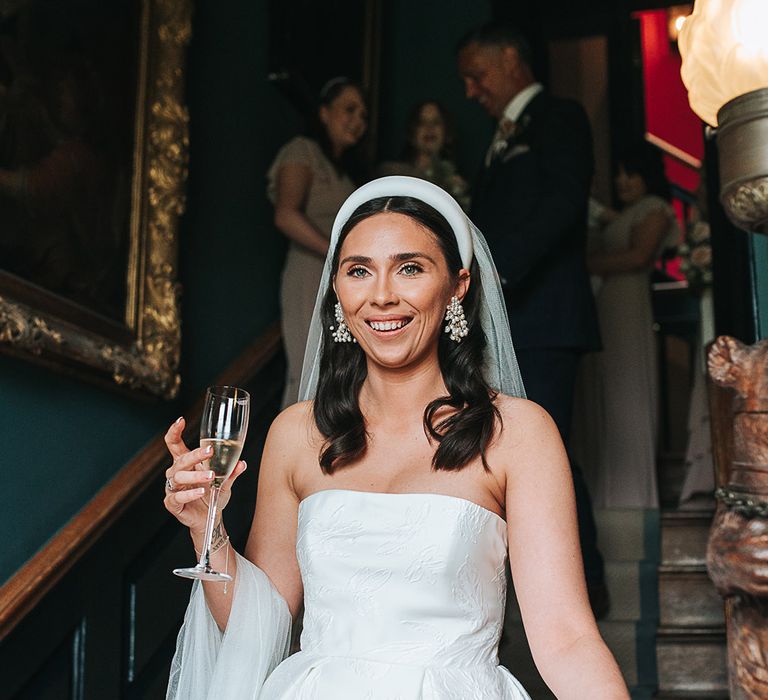 Strapless brocade Jesus Peiro wedding dress worn by bride with a chunk white headband and pearl earrings 