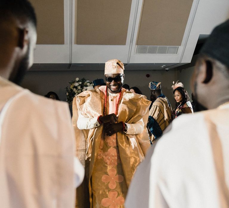 Groom wears sunglasses and traditional Nigerian formal attire for evening reception party 