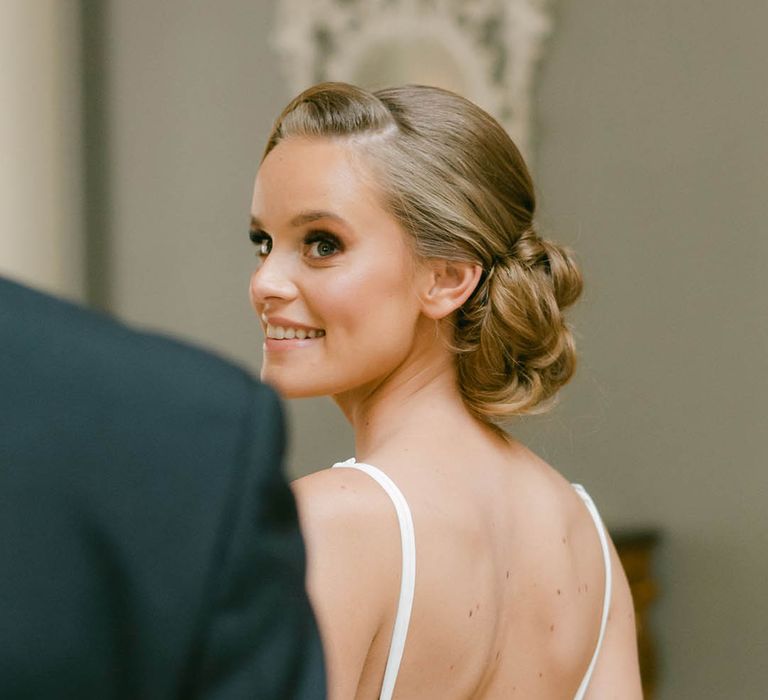 Bride smiles back at the groom as she wears her second off the shoulder outfit 