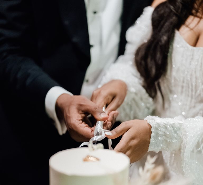 Bride & groom cut white wedding cake during outdoor ceremony 