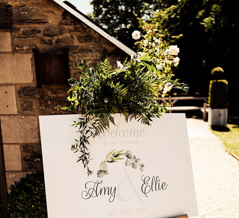 Simple and minimal wedding welcome sign with foliage decorating it 