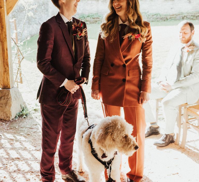 Ceri in a burgundy wedding suit with the best person in a burnt orange double breasted suit with Dug the ring bearer on a lead 