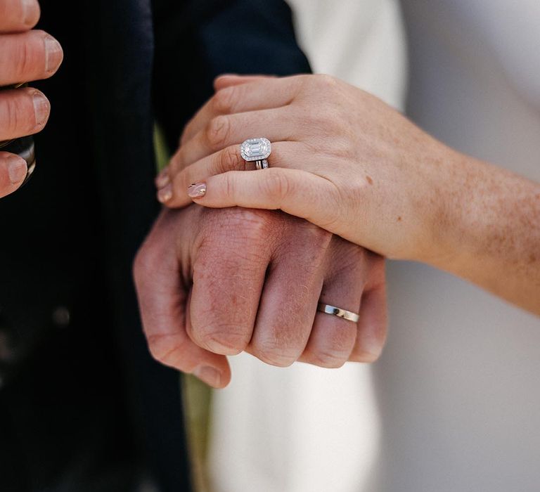 Bride and groom hold hands showing off their sparkly wedding rings 