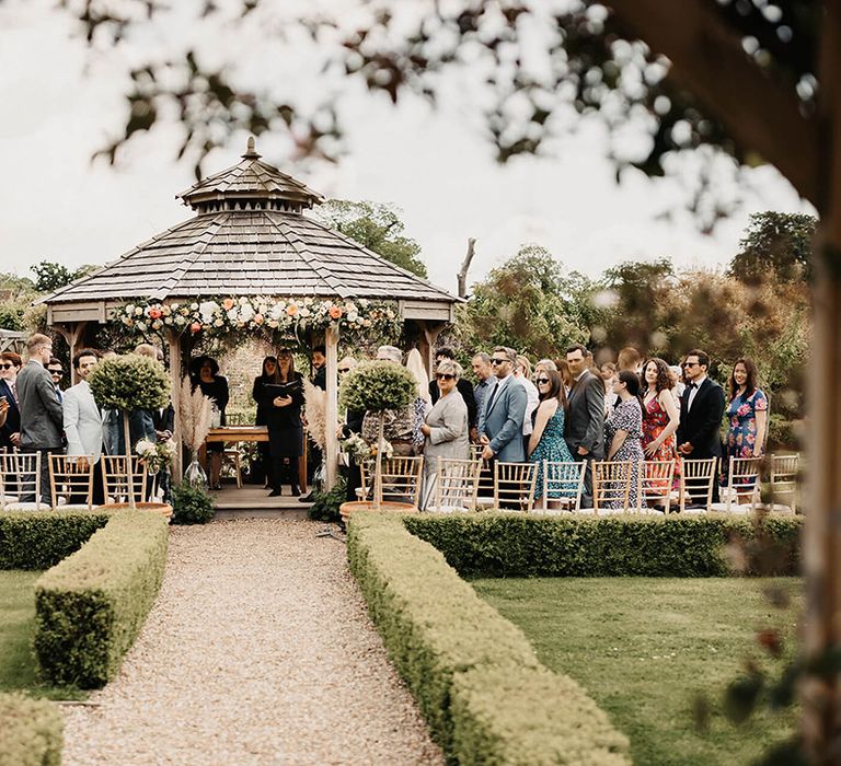 Outdoor wedding ceremony area with the guests standing for the bride's entrance