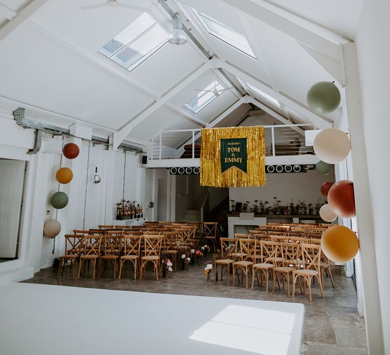 Gold streamers hang from ceiling complete with velvet banner and balloons for industrial styled retro wedding