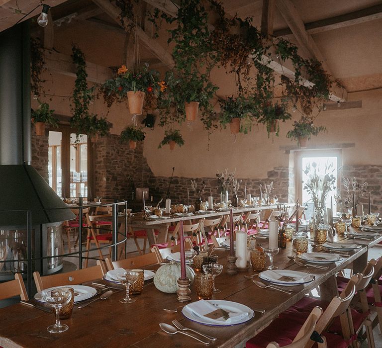 Rustic wedding with wooden tables with pumpkin table decorations complete with hanging plants in terracotta pots  