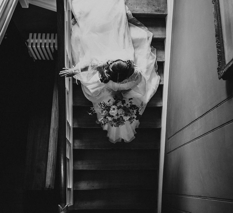 Bride walks down the stairs after getting ready for her wedding day on the way to the ceremony 