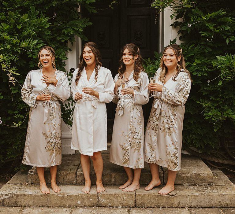 Bridesmaids in satin patterned robes standing with the bride in a white satin robe 