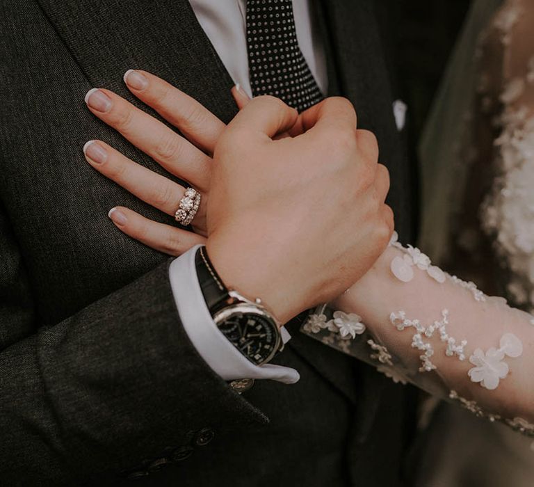 Bride with an elegant French tip style nail wearing a trinity stone diamond engagement ring and diamond wedding band 