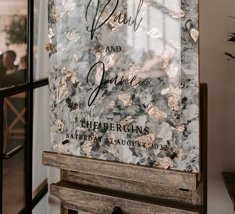 Perspex wedding sign in front of modern styled painted backdrop on wooden easel 