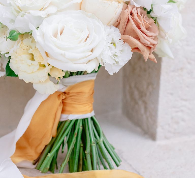 The bridal bouquet tied with white and gold silk ribbons