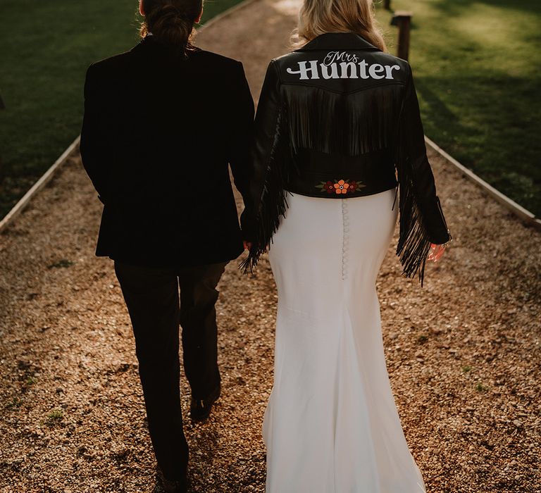 Bride in personalised handmade black leather jacket with "Mrs Hunter" written on it and floral doodles at the hem