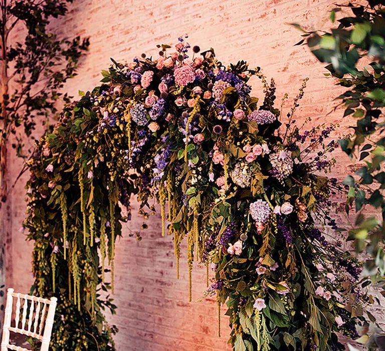 Purple and pink wedding flower moongate with lots of greenery at the wedding reception behind the top table 